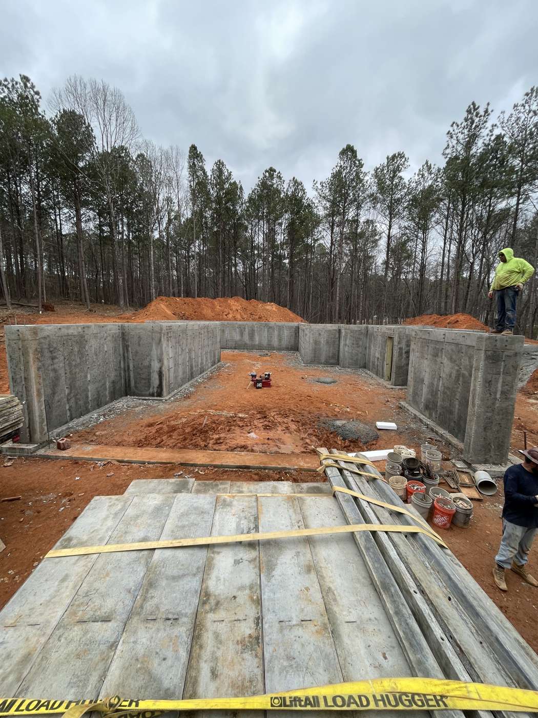 Stripped aluminum form panels stacked in front of new poured basement walls
