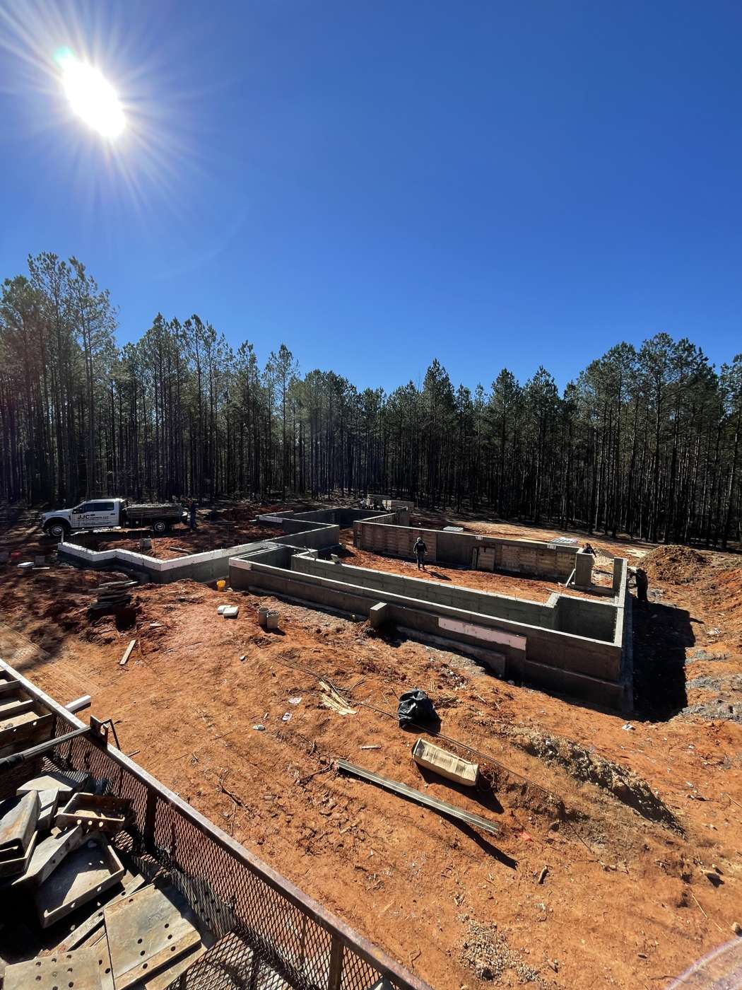 Poured concrete foundation walls on a cleared lot, form panels in the foreground