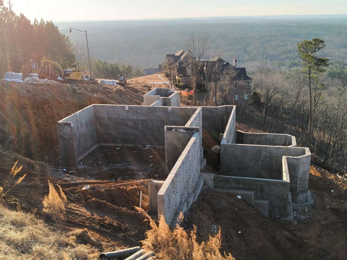 Finished poured concrete foundation walls on a hillside lot above a wooded valley